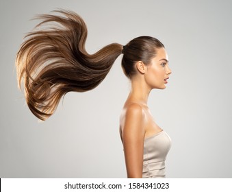 Profile Portrait Of A Beautiful Woman With A Long  Hair. Young  Brunette Model With  Beautiful Hair - Isolated On White Background. Young Girl With Straight Hair Flying In The Wind.  