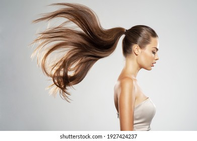 Profile portrait of a beautiful woman with a long  hair. Young  brunette model with  beautiful hair - isolated on white background. Young girl with straight hair flying in the wind.   - Powered by Shutterstock