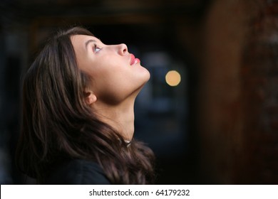 Profile Portrait Of Beautiful Young Woman Looking Up Over Dark Background. Closeup On Face, Shallow DOF.