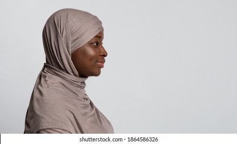 Profile Portrait Of Black Islamic Lady In Hijab Looking At Copy Space Over Light Background In Studio, Side View Shot Of Friendly Smiling African Muslim Woman In Headscarf, Panorama