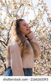 Profile Portrait Of The Caucasian Girl Shot From Below In The Beautiful Cherry Garden During The Blossoming Period, Copy Space For Text