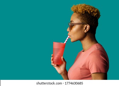 Profile portrait of a cool young  woman in pink holding a drinking cup and paper straw - Powered by Shutterstock