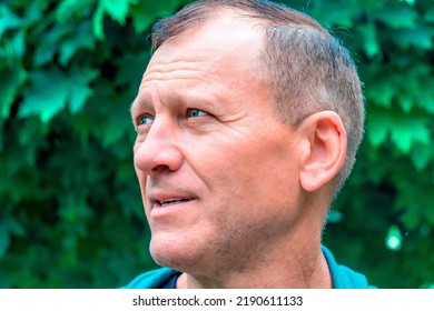 Profile Portrait Of A Handsome Mature Middle-aged Man 55 Years Old Against The Backdrop Of A Green Garden