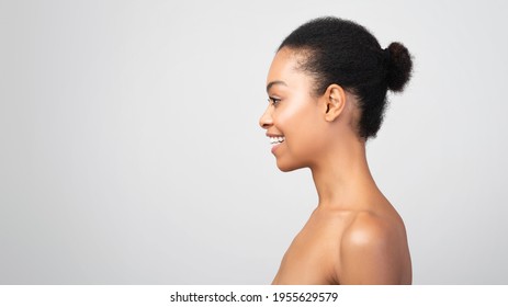 Profile Portrait Of Happy Black Woman Smiling Looking Aside At Empty Space For Text Posing Shirtless Standing On Gray Background. Panorama, Studio Shot. Side View Headshot Of Attractive African Female