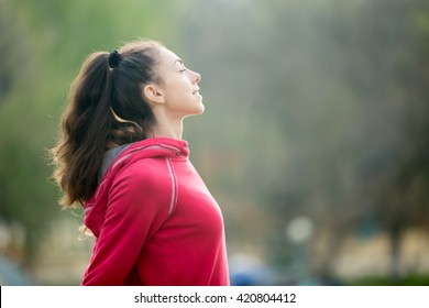 Profile portrait of happy sporty woman relaxing in park. Female model relaxing, breathing fresh air outdoors. Healthy active lifestyle concept. Copy space