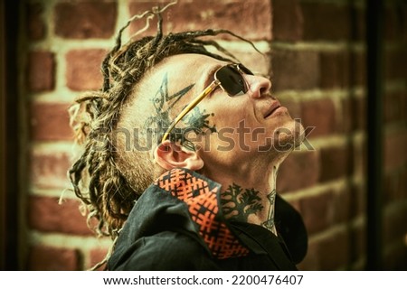Profile portrait of a  mature brutal man with ethnic tattoos on his head and neck and with punk-style Mohawk dreadlocks. Punk and rock culture. 