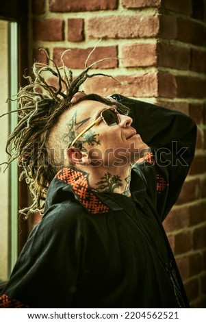 Profile portrait of a  mature brutal man with ethnic tattoos on his head and neck and with punk-style Mohawk dreadlocks. Punk and rock culture. 