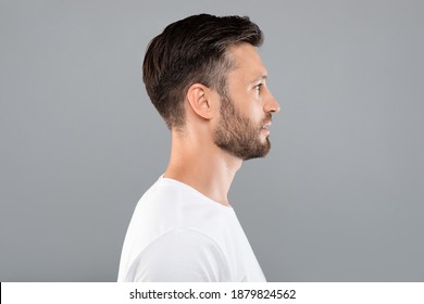 Profile Portrait Of Middle-aged Bearded Man In White T-shirt Over Grey Studio Background, Copy Space. Side View Of Handsome Confident Man Posing On Gray, Standing Straight And Looking Aside