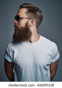 Profile portrait on turned head and long well trimmed beard of handsome man with sunglasses and white short sleeve shirt