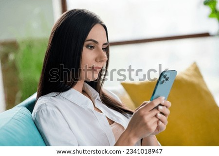 Profile portrait of pretty calm girl sitting sofa hold use smart phone chatting share blog post weekend day house indoors