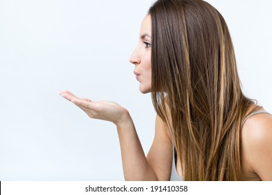 Profile Portrait Of Pretty Young Woman Blowing A Finger Kiss