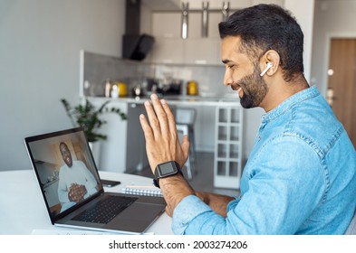 Profile Portrait Shot Of Young Indian Man Sitting At Home Desk Front Of Laptop Greeting Prof On Screen. Remote Student Practice Foreign Language Communicate Online With Native Speaker Using Internet