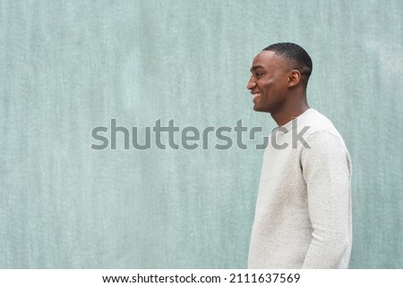Profile portrait smiling African american man by green wall