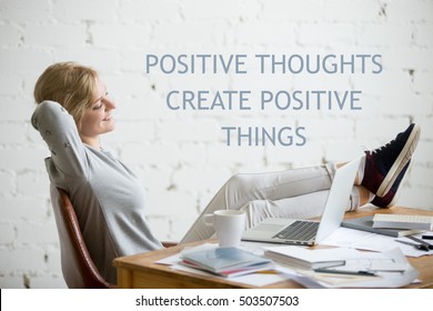 Profile portrait of smiling girl, her legs on the desk, arms behind head, laptop on the desk. Business success concept photo, lifestyle. Motivational text "Positive thoughts create positive things"