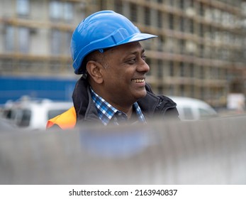 Profile Portrait Of A Smiling Indian Engineer Or Factory Worker Wearing A Safety Helmet And Looking To The Side