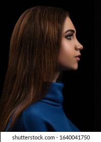 profile portrait of a young brunette woman on a black background in a blue jacket - Shutterstock ID 1640041750