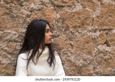 Profile portrait of a young romantic brunette woman leaning against a brick wall. Outdoors - Shutterstock ID 1939792120