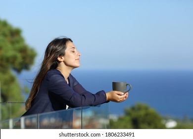 Profile of a relaxed woman in a hotel balcony with a cofee cup on the beach on summer vacation - Powered by Shutterstock