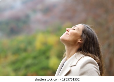 Profile of a satisfied middle aged woman breathing fresh air in a forest in winter