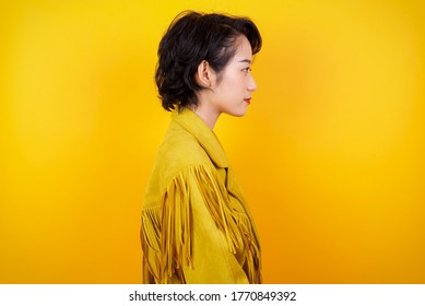 Profile Of Serious Asian Woman With Healthy Pure Skin Has Contemplative Expression Ready To Have Outdoor Walk Isolated Over Grey Studio Wall With Copy Space.