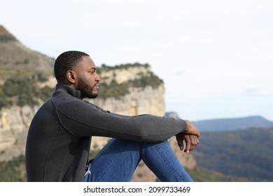 Profile of a serious man with black skin contemplating sitting in the mountain