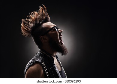Profile shot of an angry punk rocker shouting on dark background