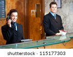 Profile shot of attractive executives at the reception of a hotel. Woman attending phone call
