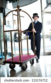 Profile shot of doorman holding cart at the entrance of hotel