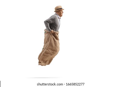 Profile Shot Of An Elderly Man Jumping In A Sack And Playing Gunny Race Isolated On White Background