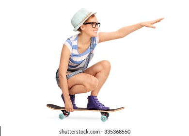 Profile Shot Of A Hipster Girl Riding A Skateboard And Pointing Forward With Her Hand Isolated On White Background