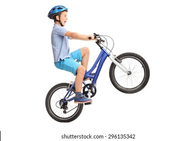 Profile Shot Of A Little Boy With Blue Helmet Doing A Wheelie On A Small Blue Bike Isolated On White Background