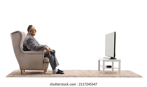 Profile Shot Of A Mature Man In A Bathrobe Sitting In An Armchair And Watching Tv Isolated On White Background