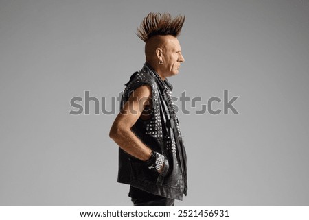 Profile shot of a punk man with a mohawk isolated on gray background