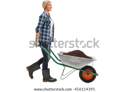 Profile shot of a young cheerful woman pushing a wheelbarrow full of dirt isolated on white background