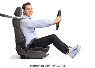 Profile shot of a young man driving seated on car seat and looking at the camera isolated on white background 