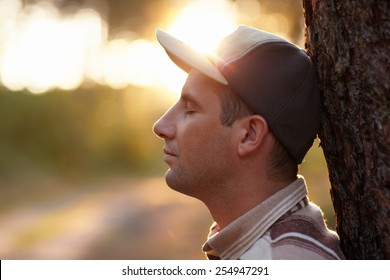 Profile shot of a young man with his eyes closed meditatively in an early morning forest