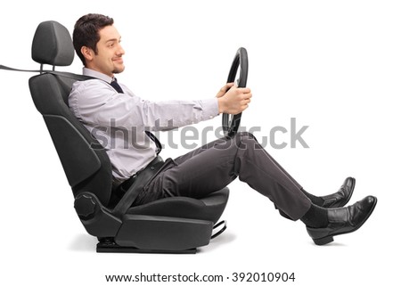 Profile shot of a young man holding a steering wheel seated on a car seat isolated on white background