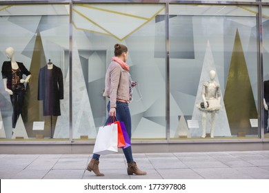 Profile Shot Of Young Woman With Shopping Bags Looking At Window Display