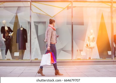 Profile Shot Of Young Woman With Shopping Bags Looking At Window Display