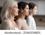 Profile side faces view of serious attractive grandmother posing with grown up daughter and little granddaughter standing together in row, three generations of women, family unity, bonding and ties