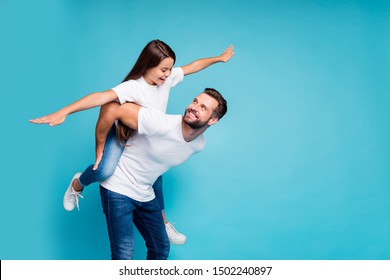 Profile side photo of cheerful people holding hands playing piggyback wearing white t-shirt denim jeans  isolated over blue background
