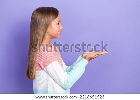 Profile side photo of cute positive girl arm demonstrate look empty space dressed stylish sweater isolated on purple color background