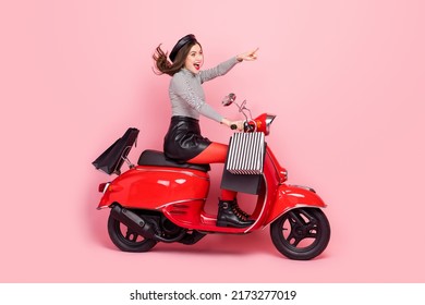 Profile Side Photo Of Excited Stylish Lady Drive Fast Motor Bike Vehicle Point Finger Shop Offer Isolated Pink Color Background