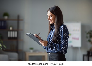 Profile side photo of happy charming woman hold clip board write plan list good mood in office indoors workplace