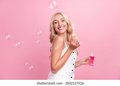 Profile side photo of young girl happy positive smile air fly soap bubbles isolated over pink color background