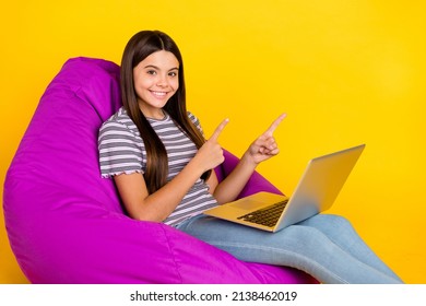 Profile side photo of young girl sit chair indicate fingers empty space promo select use laptop isolated over yellow color background - Powered by Shutterstock