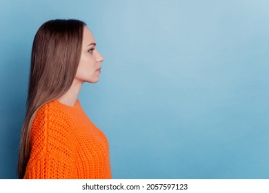 Profile side photo of young woman calm look empty space wear orange sweater isolated blue color background