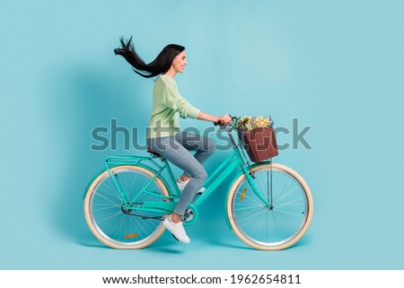 Profile side view of attractive cheerful girl riding bike having fun air blowing hair isolated over bright blue color background
