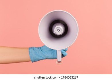 Profile Side View Closeup Of Human Hand In Blue Surgical Gloves Holding Megaphone. Indoor, Studio Shot, Isolated On Pink Background.