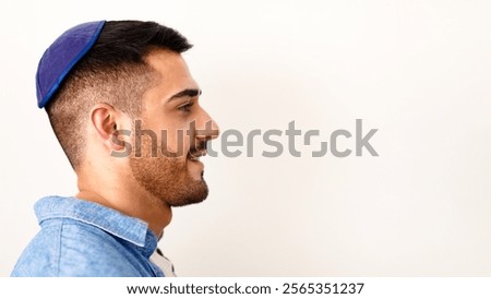Profile side view headshot portrait of handsome smiling jewish guy posing at studio, looking aside, wearing kippah, posing isolated on light white studio background, copy free space, advert banner
